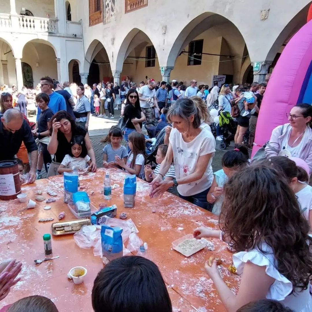 La dottoressa Barbara Camilli partecipa attivamente a un evento pubblico dell'Associazione Psicologia Utile APS in una piazza di Novara, coordinando un laboratorio creativo all'aperto al tavolo con numerosi bambini.