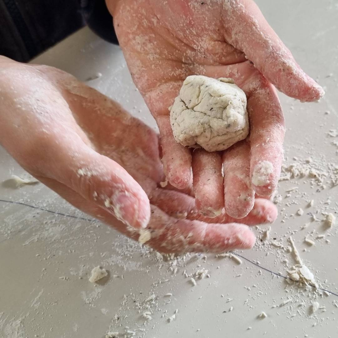 Primo piano ravvicinato di mani di un giovane studente ricoperte di farina mentre manipolano un impasto durante un laboratorio pratico di cucina e benessere, all'interno del percorso di educazione alimentare per ragazzi a Novara della Dott.ssa Barbara Camilli.
