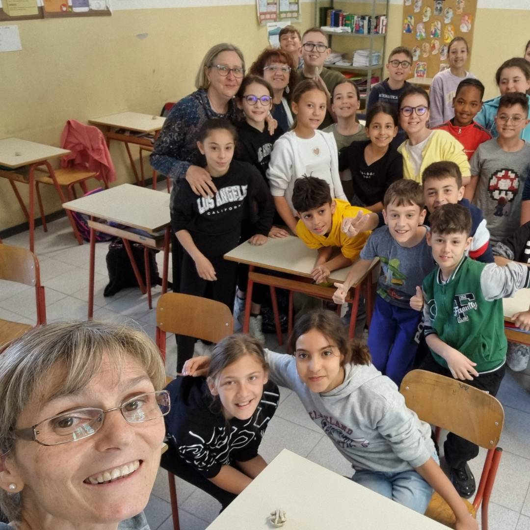 Selfie della Dott.ssa Barbara Camilli sorridente all'interno di un'aula scolastica insieme a un gruppo di alunni e insegnanti durante una sessione didattica del progetto Nutriziopoli, focalizzato sull'educazione alimentare per ragazzi a Novara.