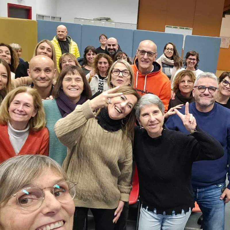 La dottoressa Barbara Camilli in primo piano sorride insieme a un gruppo affiatato di partecipanti durante i suoi corsi di formazione per professionisti incentrati sul benessere organizzativo e sulla gestione del burnout.